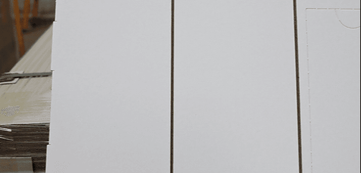 Die-cut white laminated boards prepared for rigid gift box assembly in luxury packaging production process