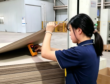Worker measuring moisture content of grey board during packaging material quality inspection