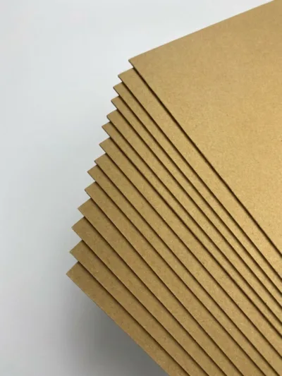 Brown kraft paper sheets stacked in warehouse for packaging, wrapping, and paper bag production