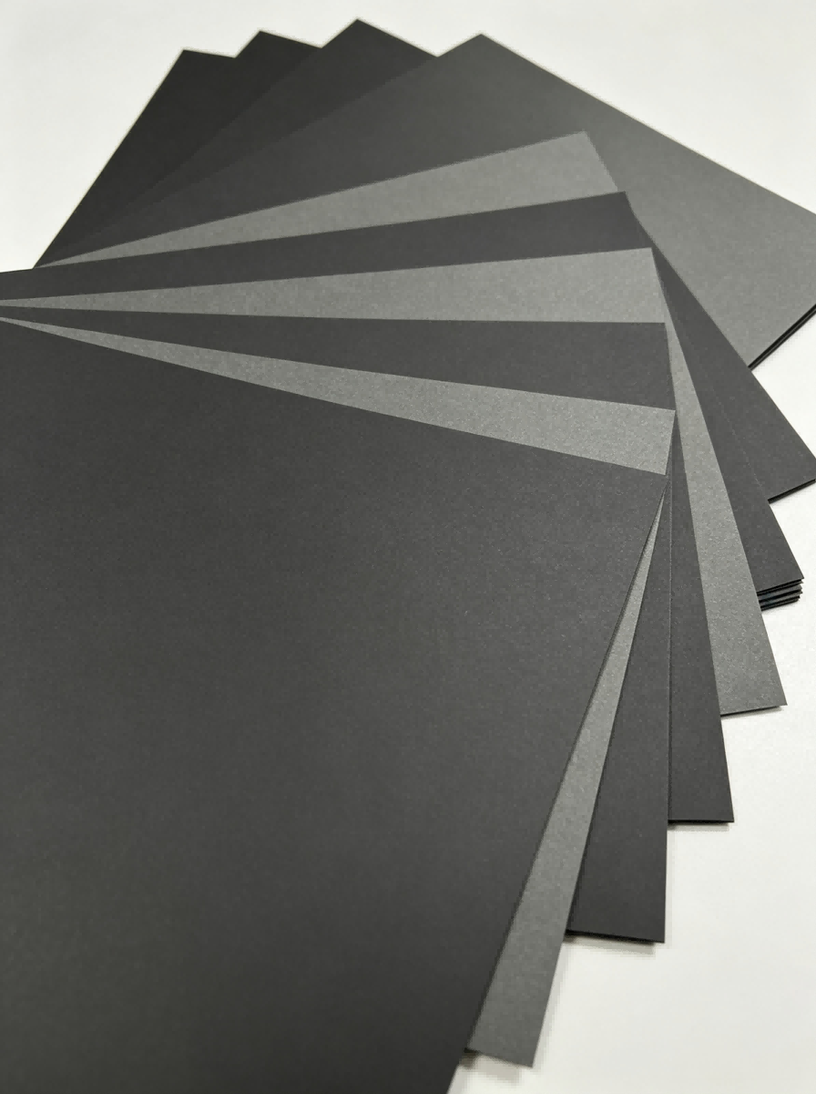 Single‑Sided Through‑Black Paperboard fan layout, assorted black & dark grey matte cardboard sheets flat lay, solid core black paper board sample set Single‑Sided Through‑Black Paperboard fan layout, assorted black & dark grey matte cardboard sheets flat lay, solid core black paper board sample set