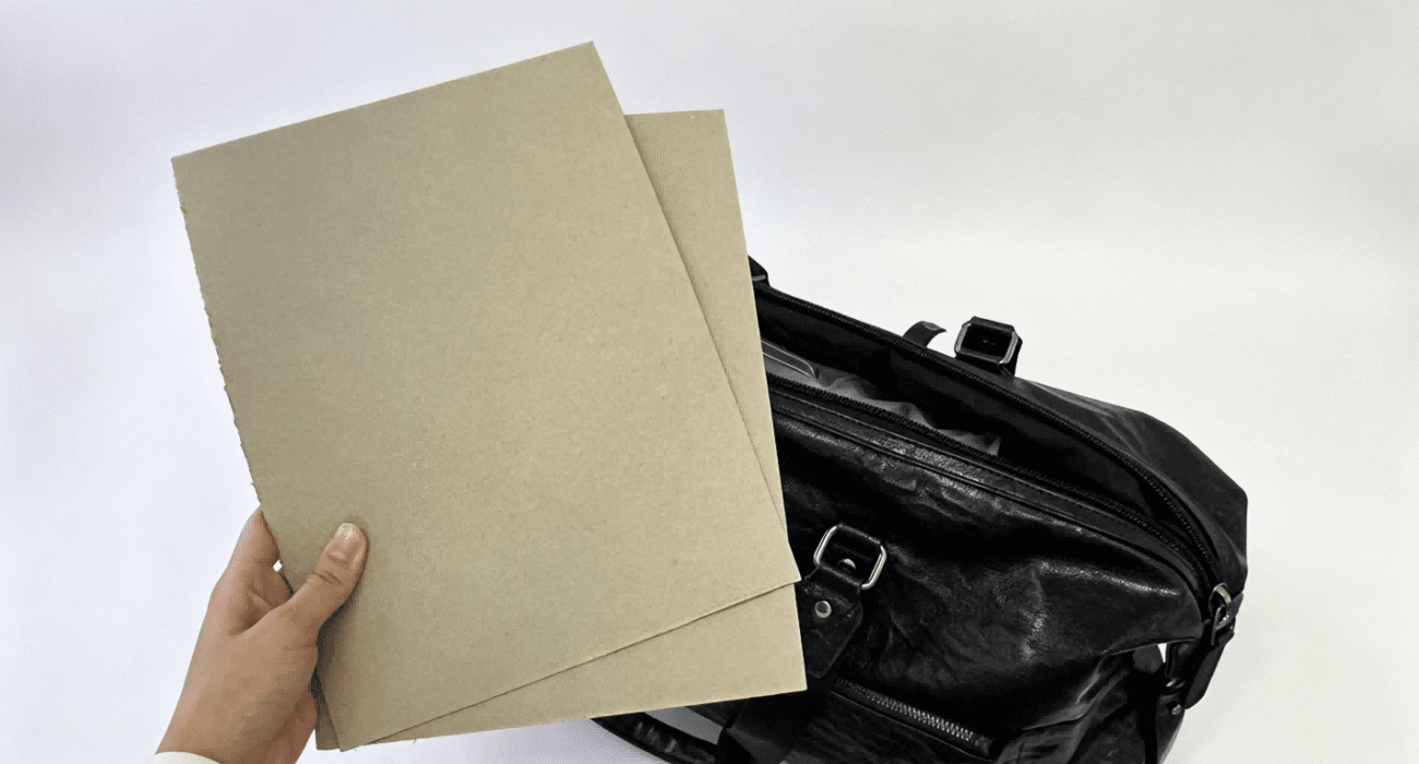 Greyboard sheets displayed next to black travel bag, greyboard material for bag stiffener